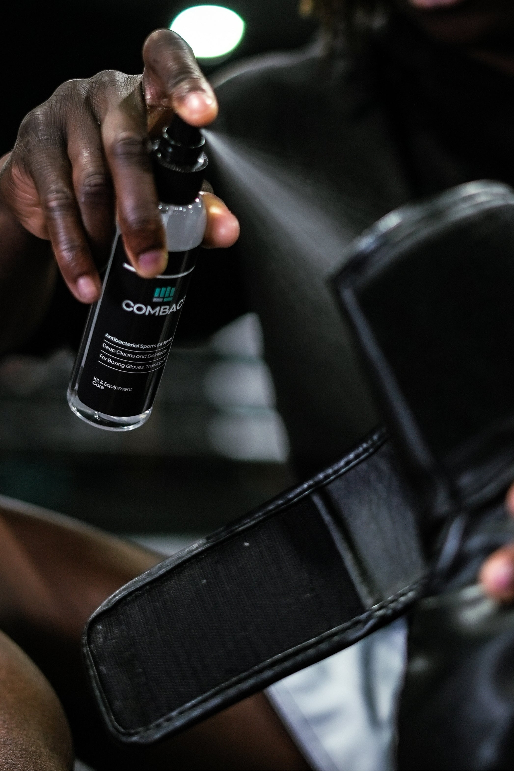 Spraying boxing gloves with boxing glove cleaning spray after training