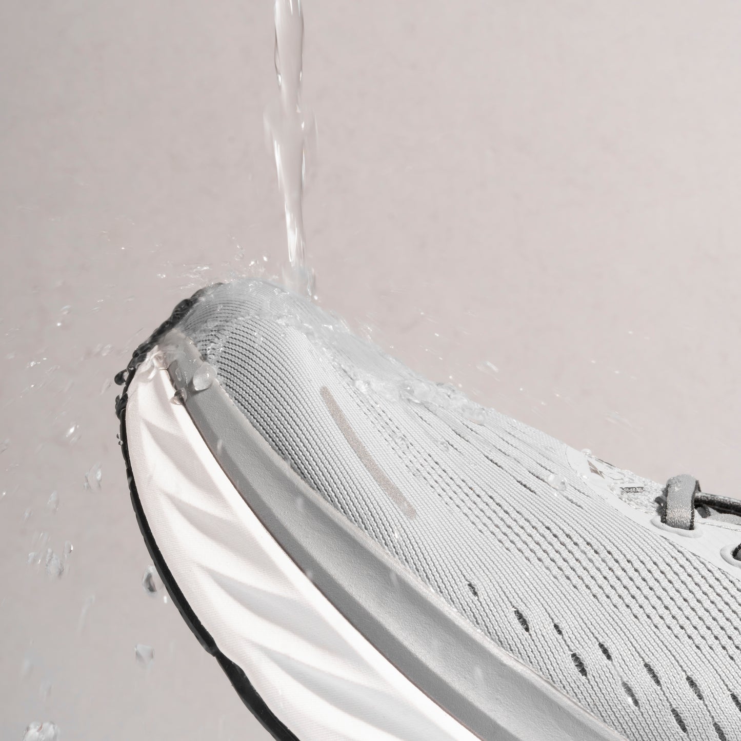 Professional photograph of water being poured onto running trainer, but the running trainer is being protected by Waterproof Fabric Spray. Running trainer is waterproof due to use of a running trainer waterproof protector spray