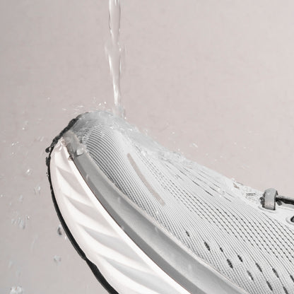 Professional photograph of water being poured onto running trainer, but the running trainer is being protected by Waterproof Fabric Spray. Running trainer is waterproof due to use of a running trainer waterproof protector spray